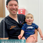 Dr. David Yates smiles while holding an infant patient