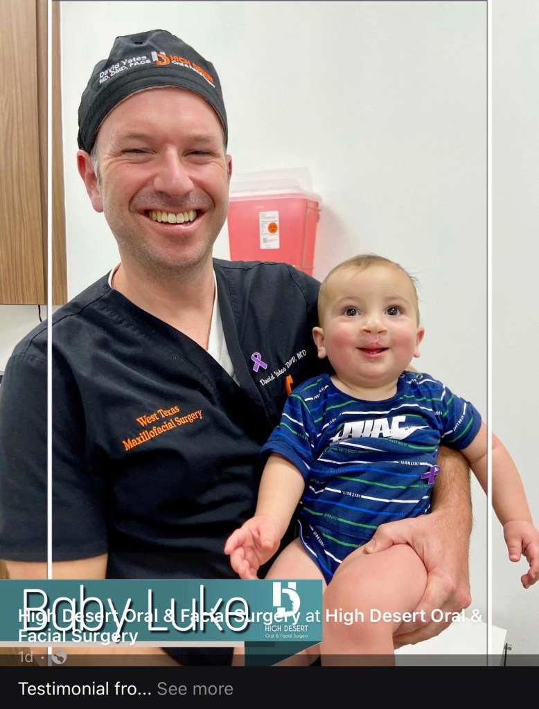 Dr. David Yates smiles while holding an infant patient