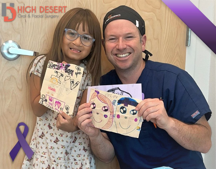 Dr. Yates and child patient hold drawings