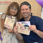 Dr. Yates and child patient hold drawings