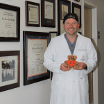 Dr. Yates stands next to awards