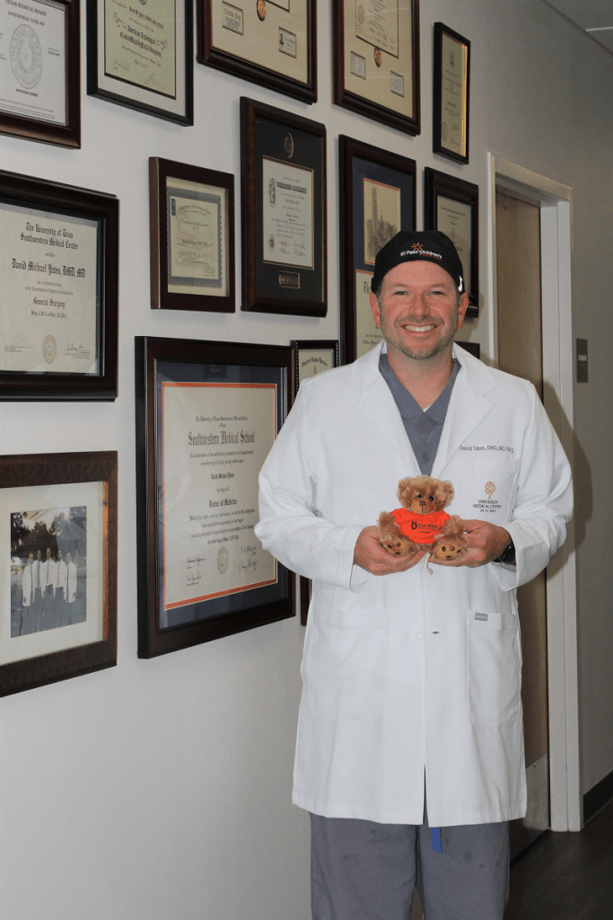 Dr. Yates stands next to awards